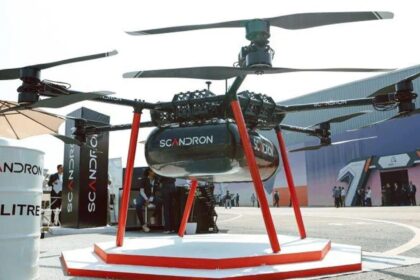 SCM Spectrum - Scandron CargoMax 20KHC drone carrying a heavy payload, showcasing its autonomous flight capabilities over rugged terrain.