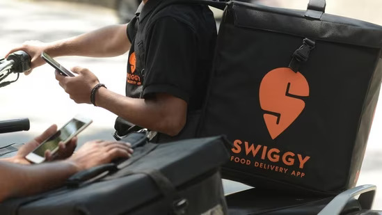 SCM Spectrum - Swiggy delivery riders preparing for orders as the company invests $120M in Scootsy to enhance logistics and supply chain.